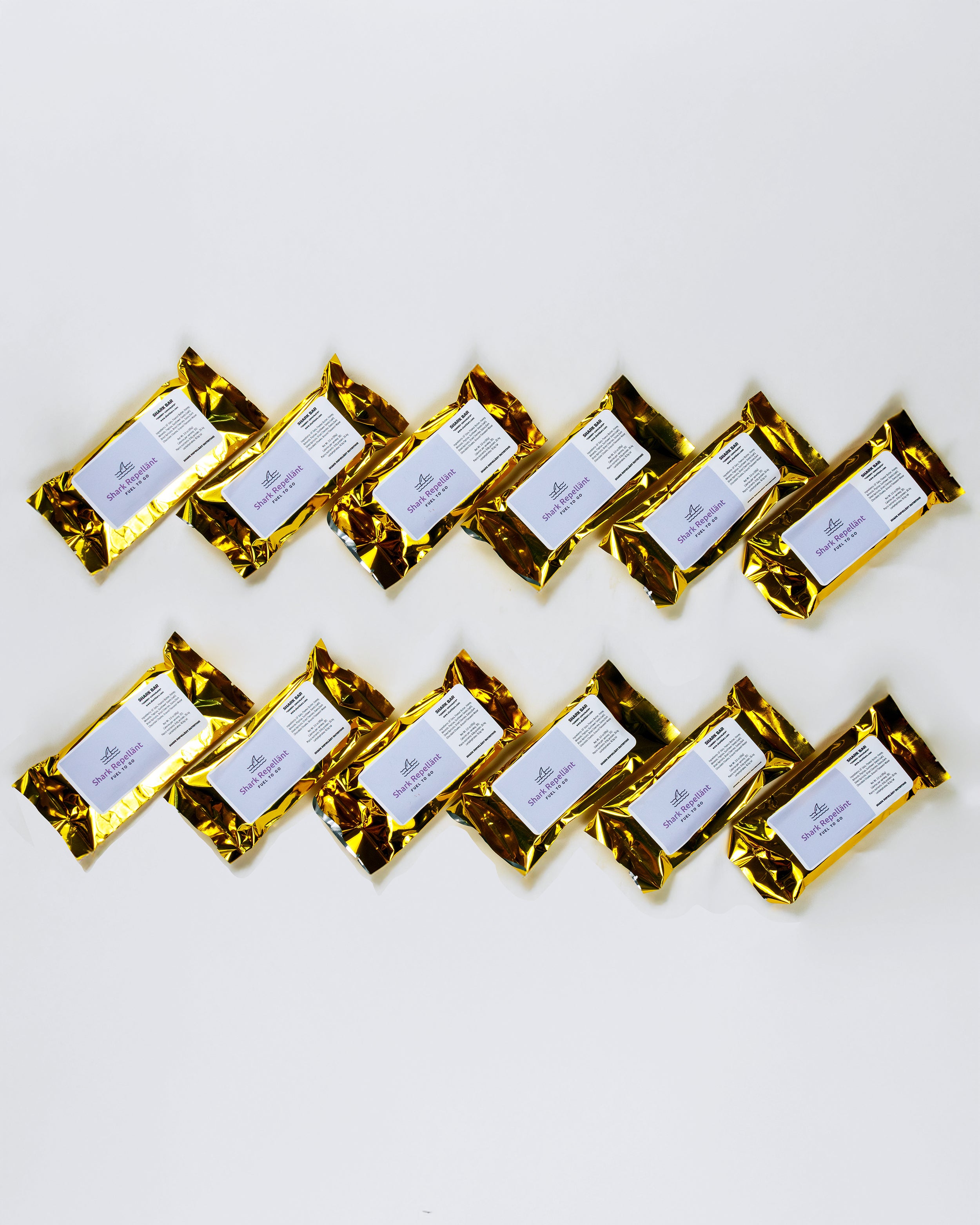12 Gold-wrapped cherry chocolate Shark Bars with labels arranged in a zigzag pattern on a white background